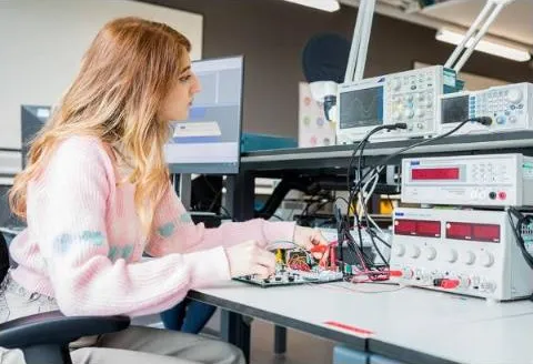 An engineer testing circuit boards at an electronics workbench